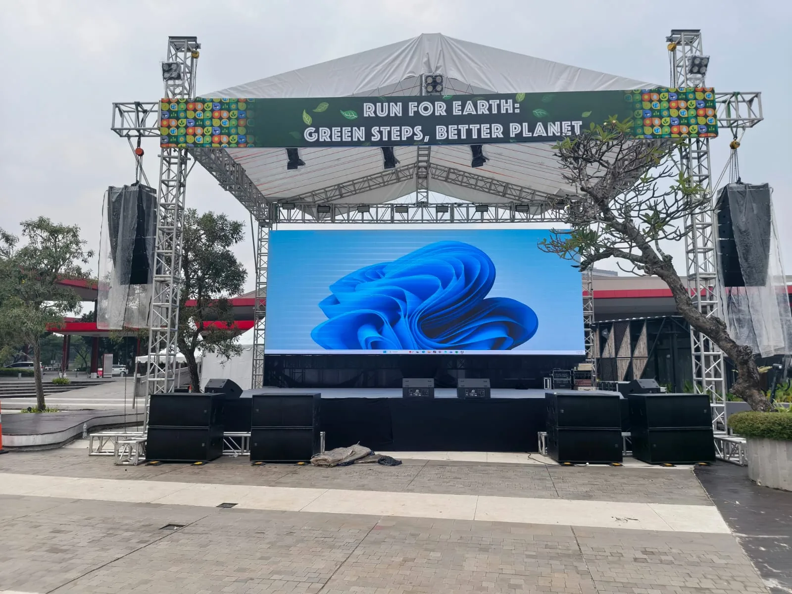 Panggung outdoor dengan layar LED dan speaker line array di Run For Earth.