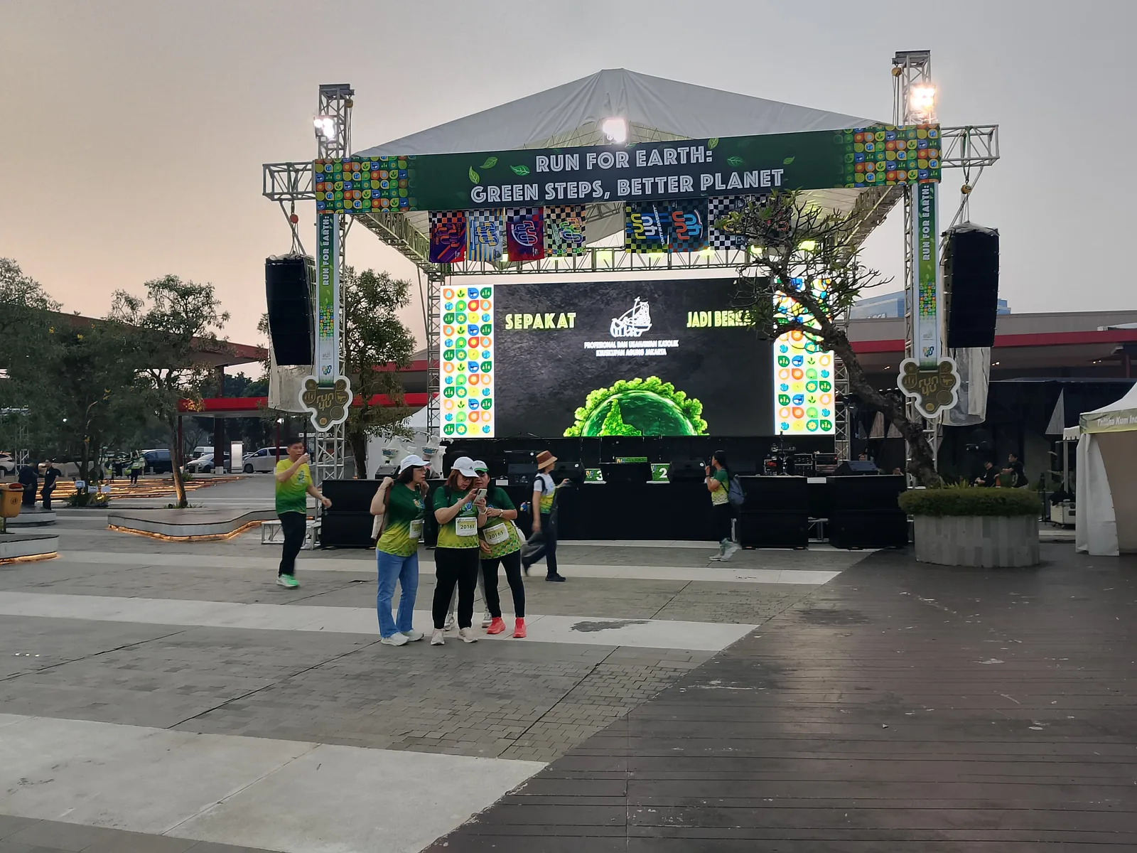 Layar LED menyala dan panggung saat senja di Run For Earth.