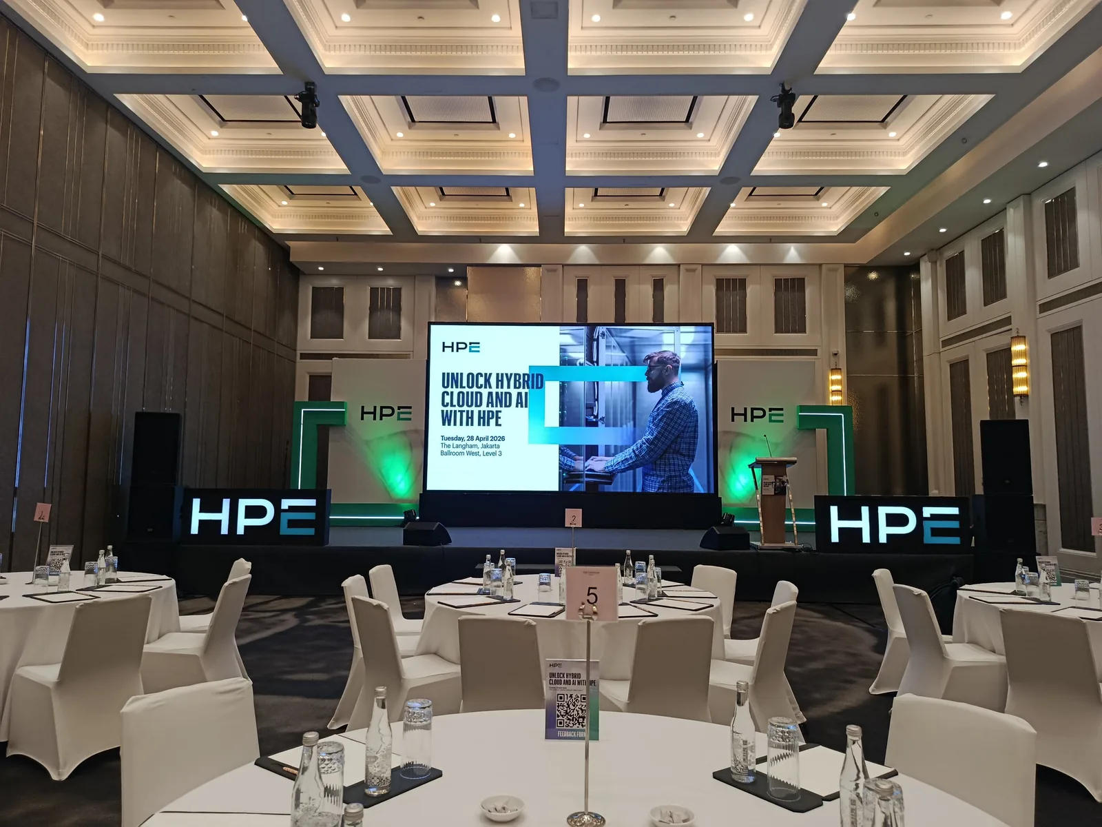 Panggung dengan layar LED dan logo HPE menyala pada acara HPE di Ballroom The Langham Jakarta.